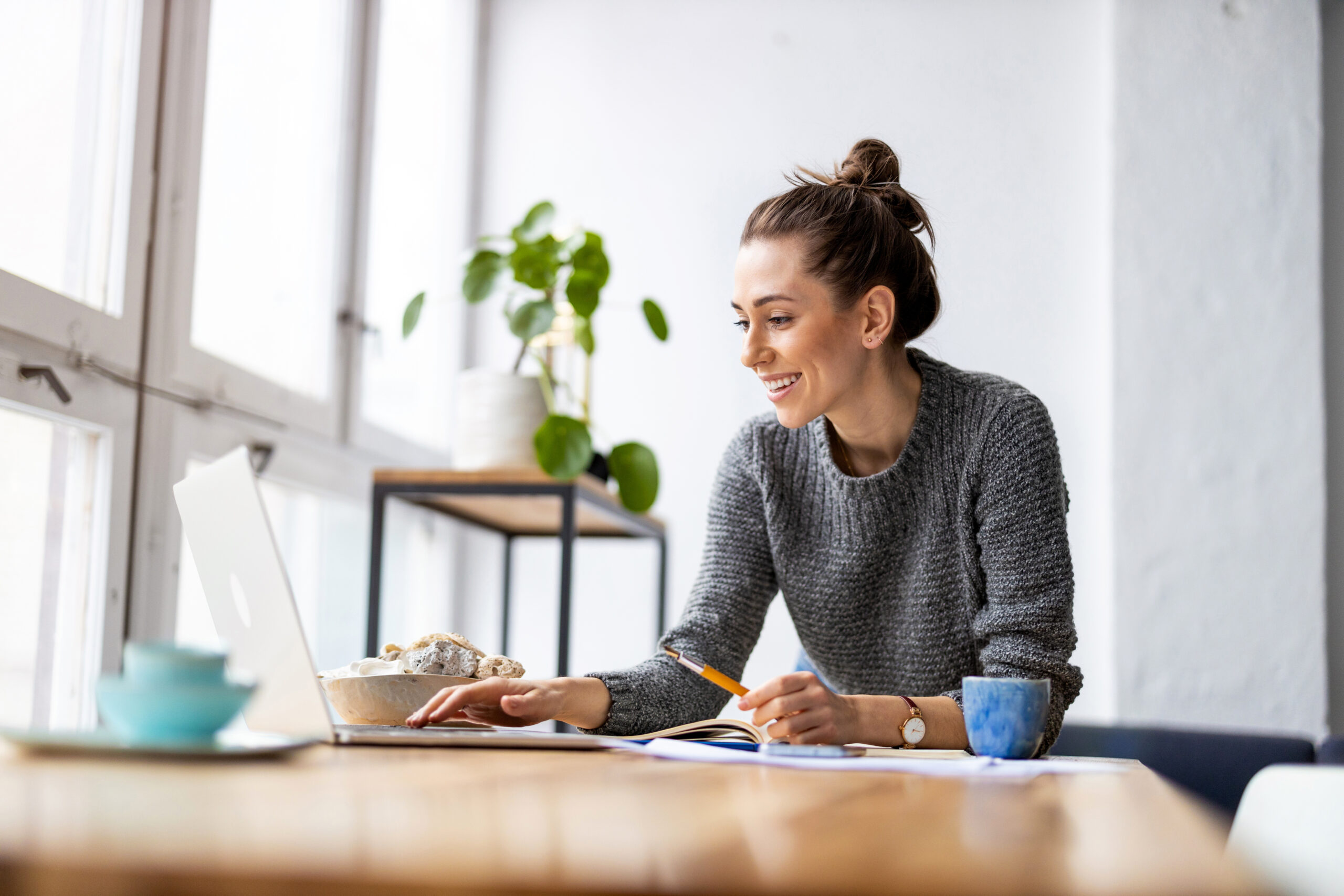 Femme qui travaille à un bureau d'ordinateur avec plante et meuble en bois